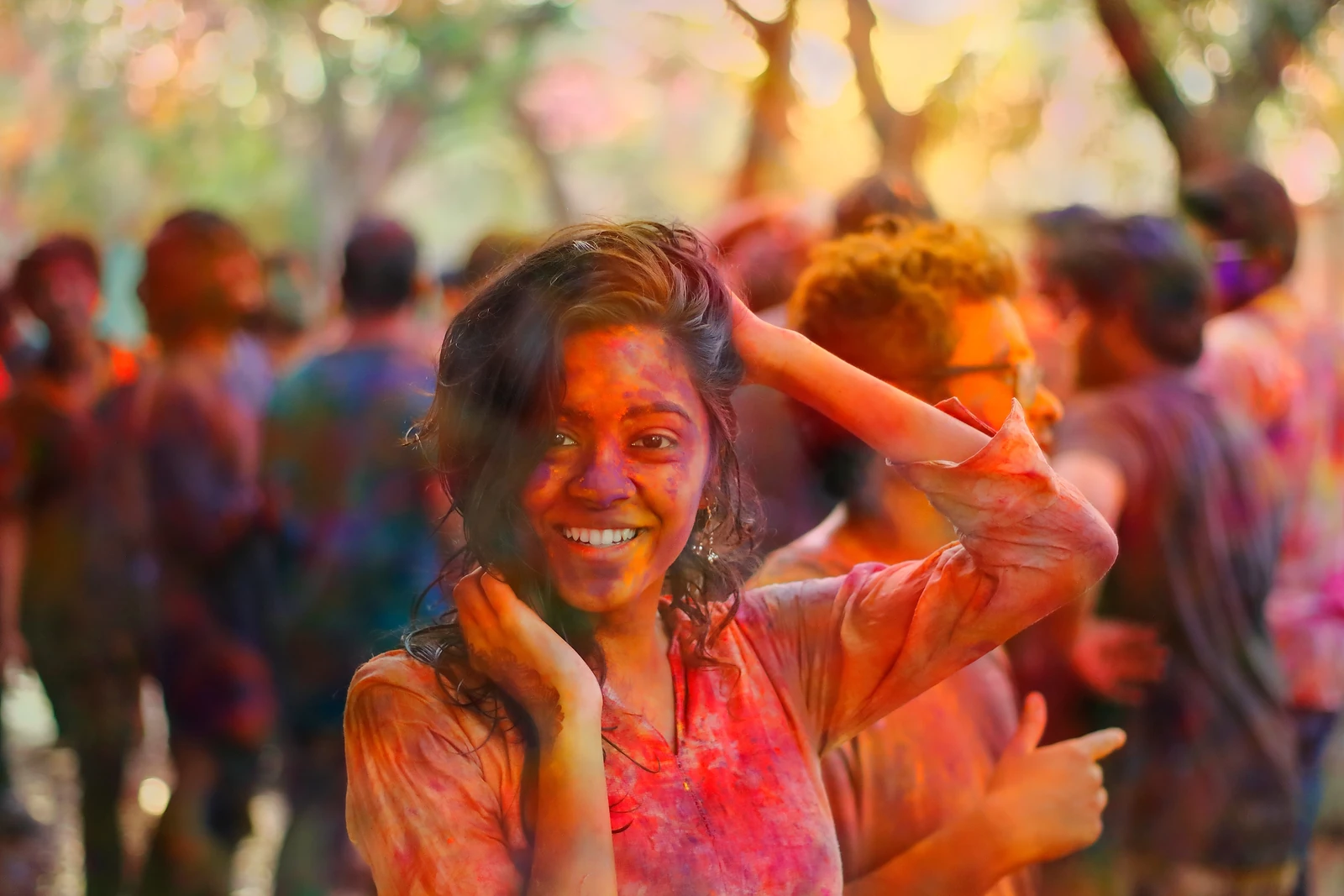 A woman covered in coloured powder laughing during Holi
